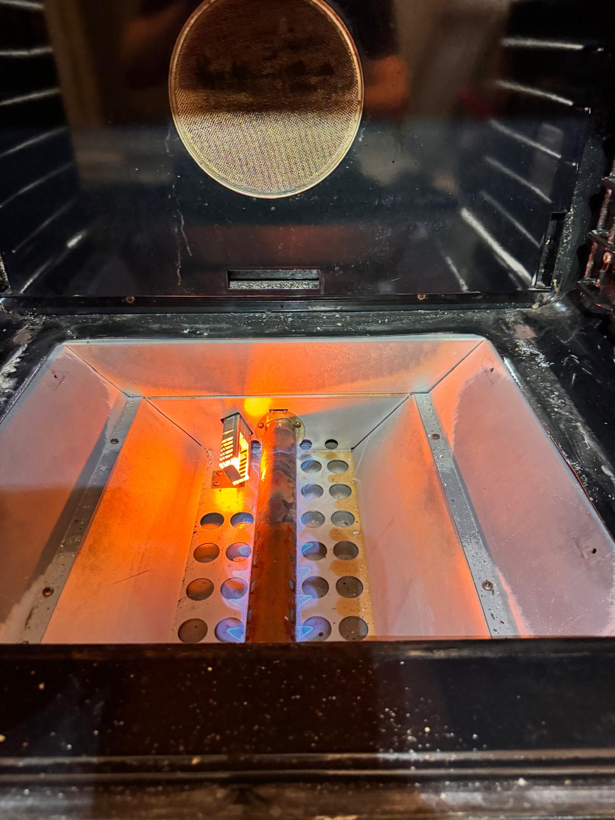Gas oven burner and glowing igniter during service